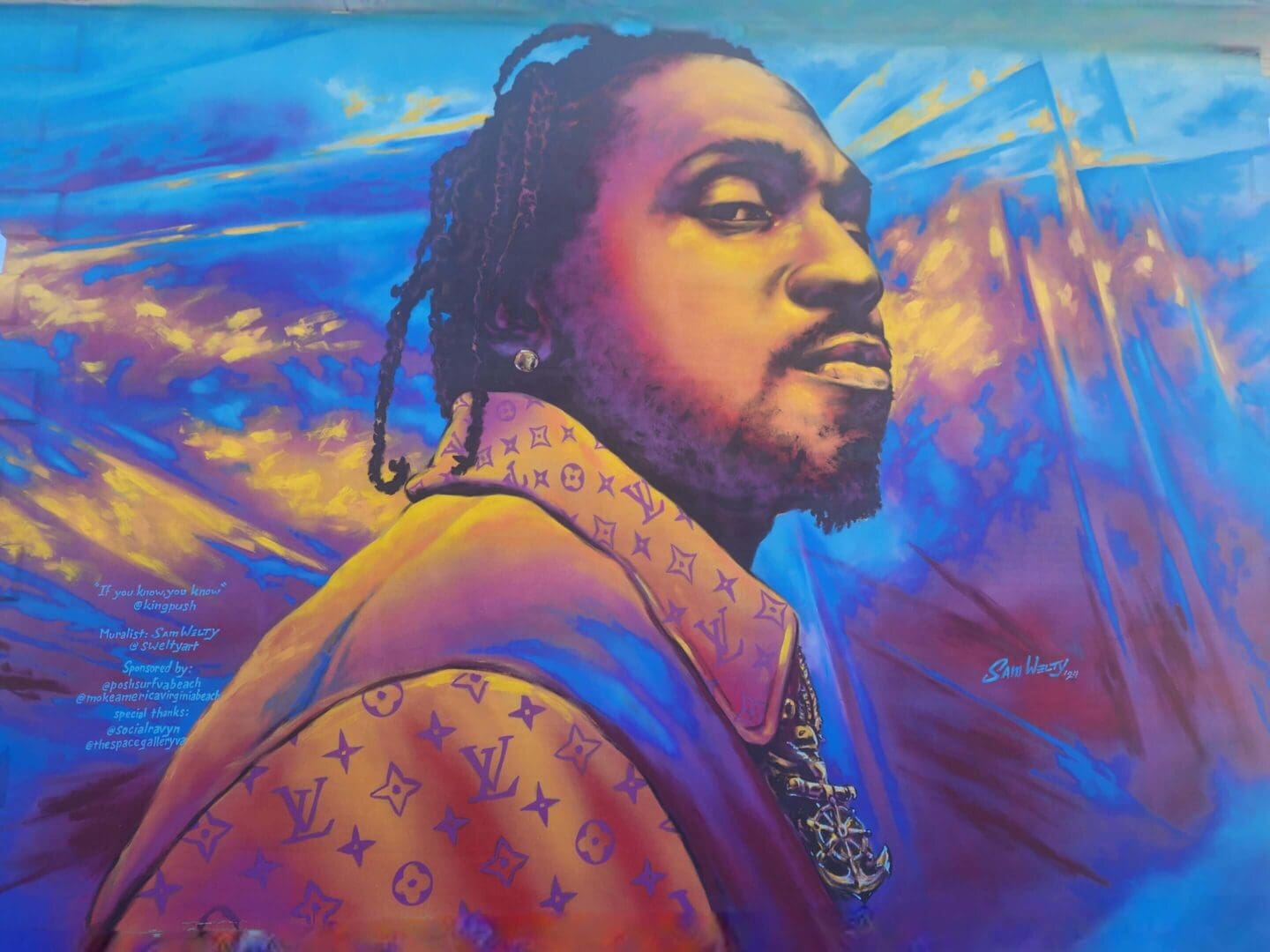 Colorful mural of a man with braided hair against a vibrant sky.