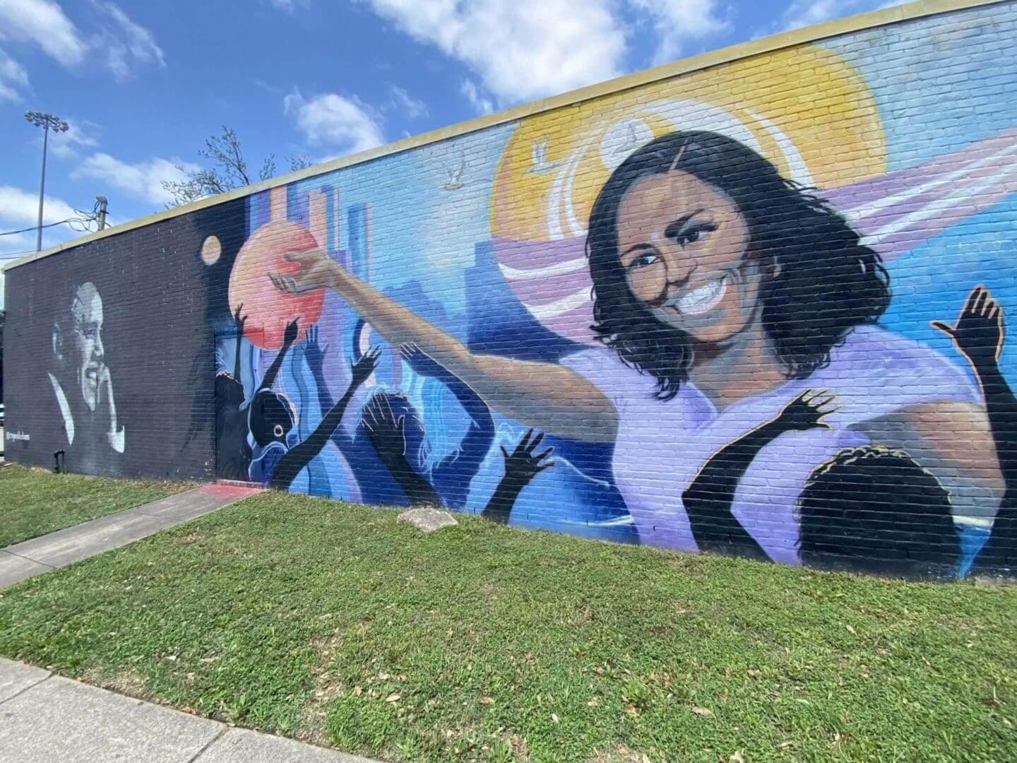 Mural of a woman with a halo giving a thumbs-up on a sunny day.