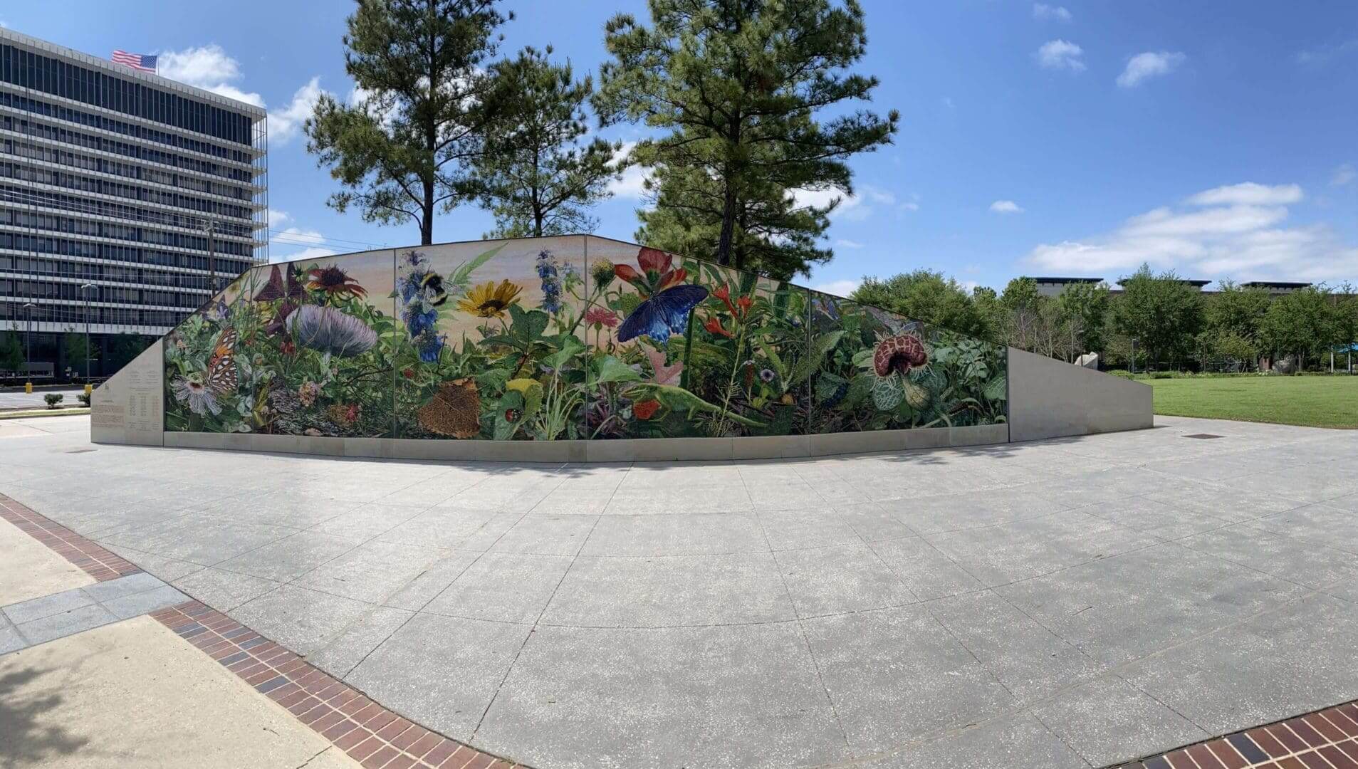 Colorful mural with flowers and butterflies on a wall behind trees.