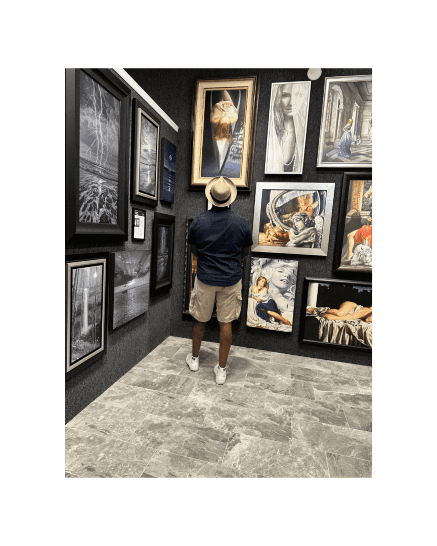 A man arranging framed artwork on a gallery wall.