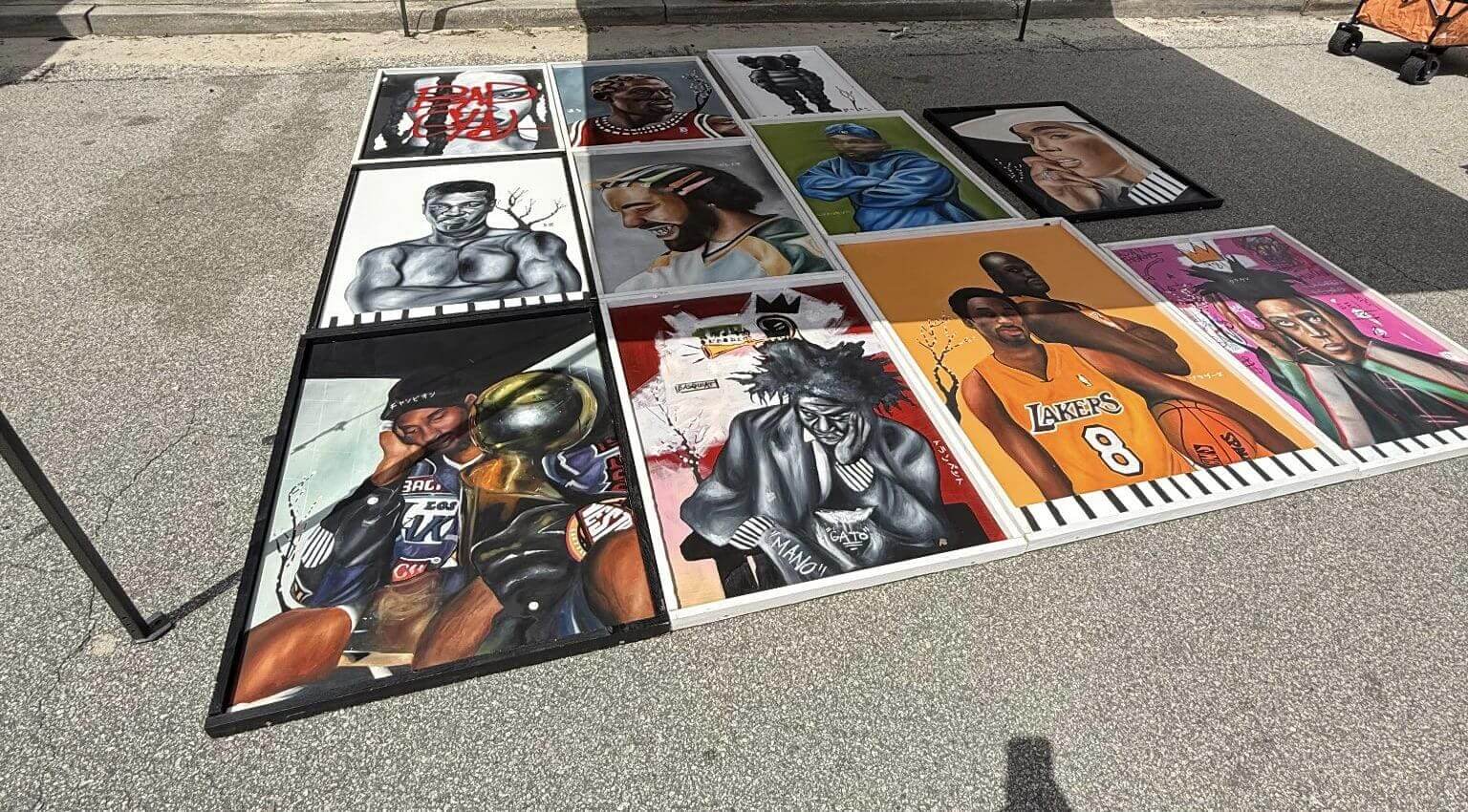 A collection of colorful superhero and comic art prints displayed outdoors.