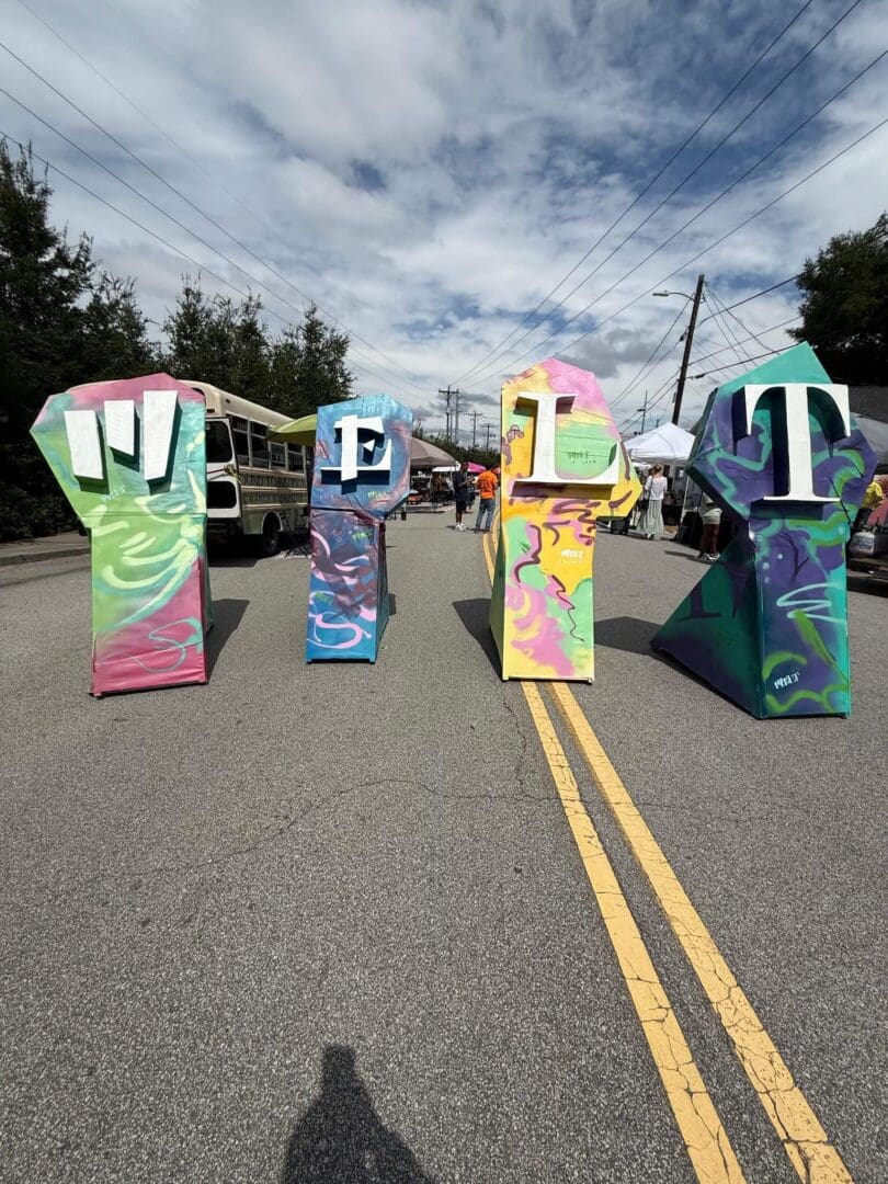Colorful hand sculptures spell out "LIFT" on a road.