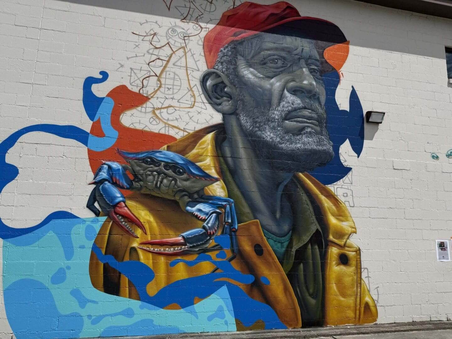 Mural of an elderly man with a crab on his shoulder, blending realism and abstract art.
