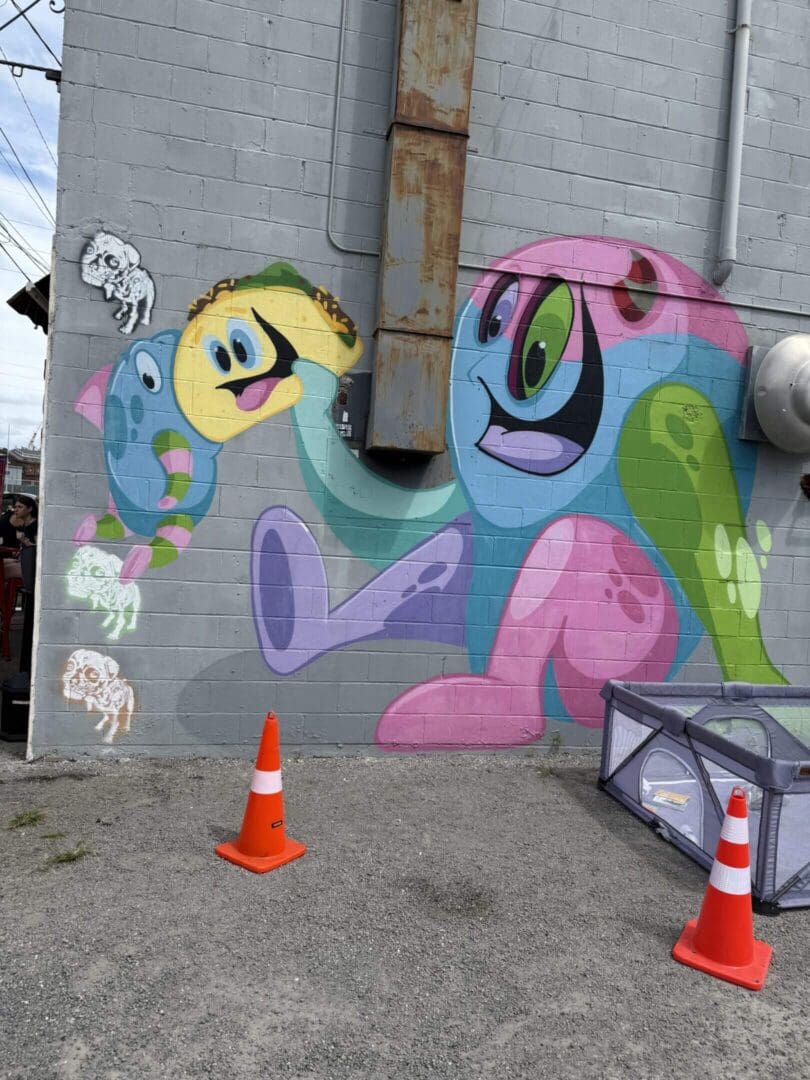 Colorful cartoon-style graffiti of playful creatures on a gray wall.