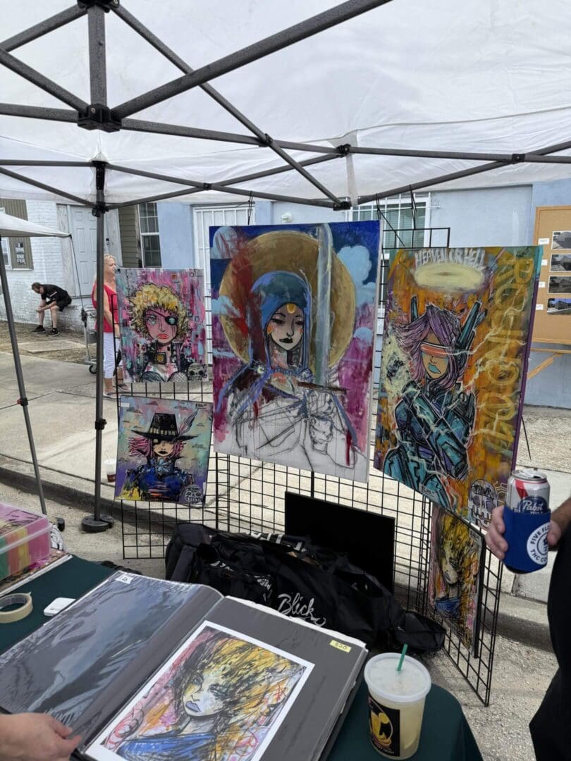 Anime-style posters displayed at an outdoor art booth.