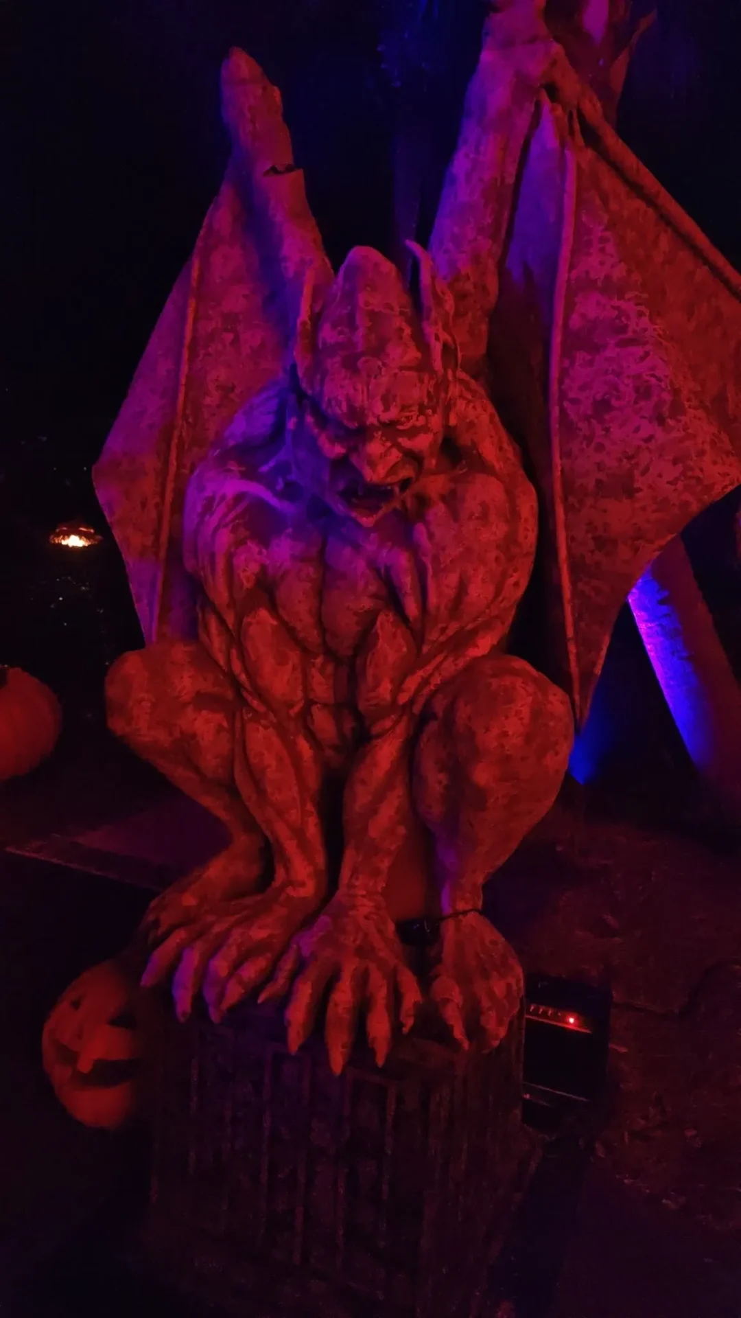 Gargoyle statue illuminated by eerie red light.