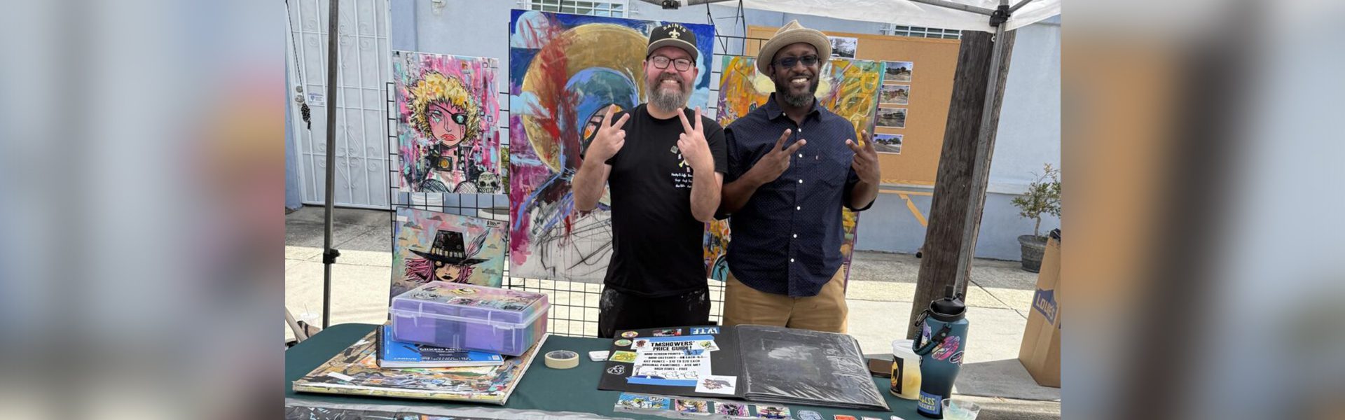 Two men smiling at art booth.