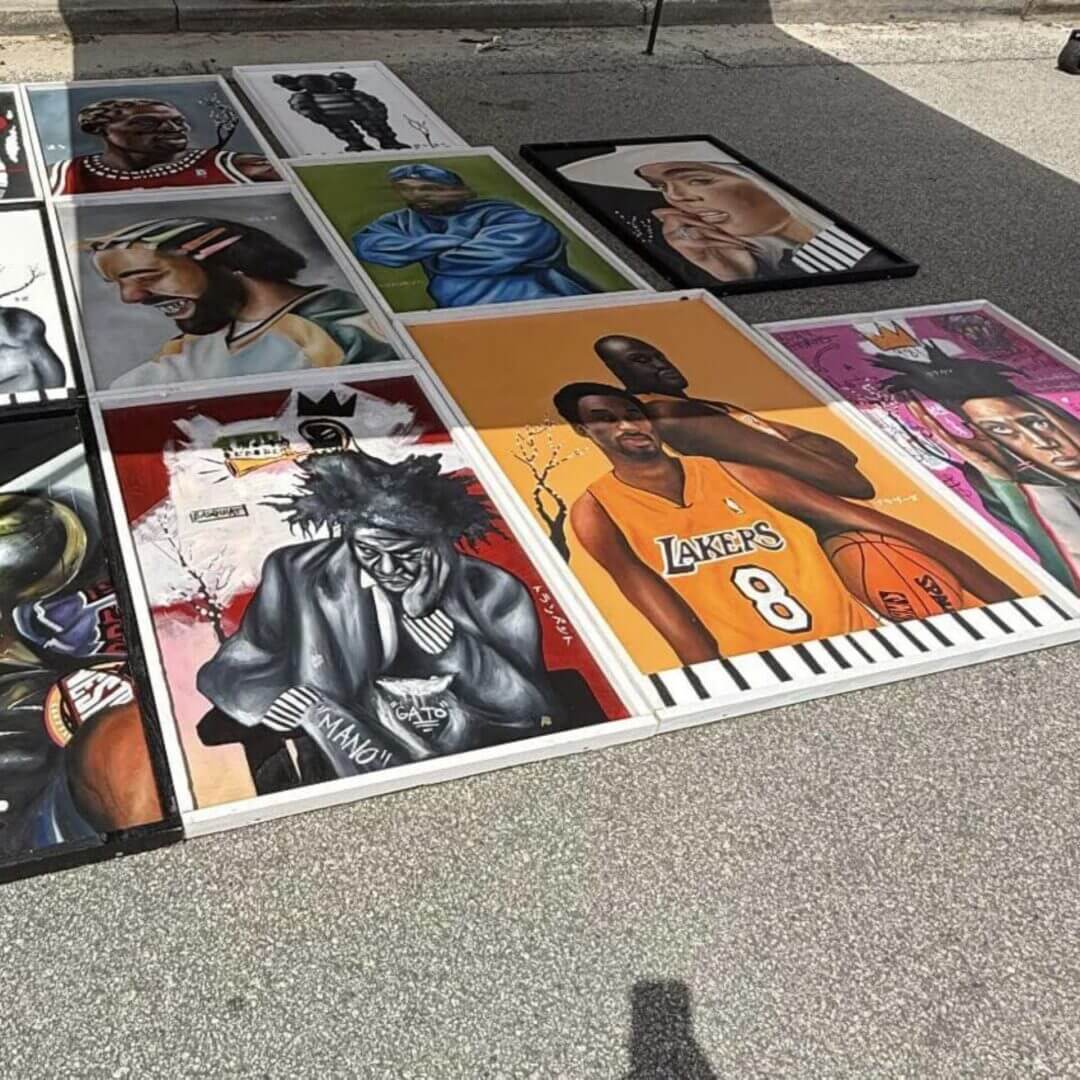 Assorted portrait paintings displayed on the ground.