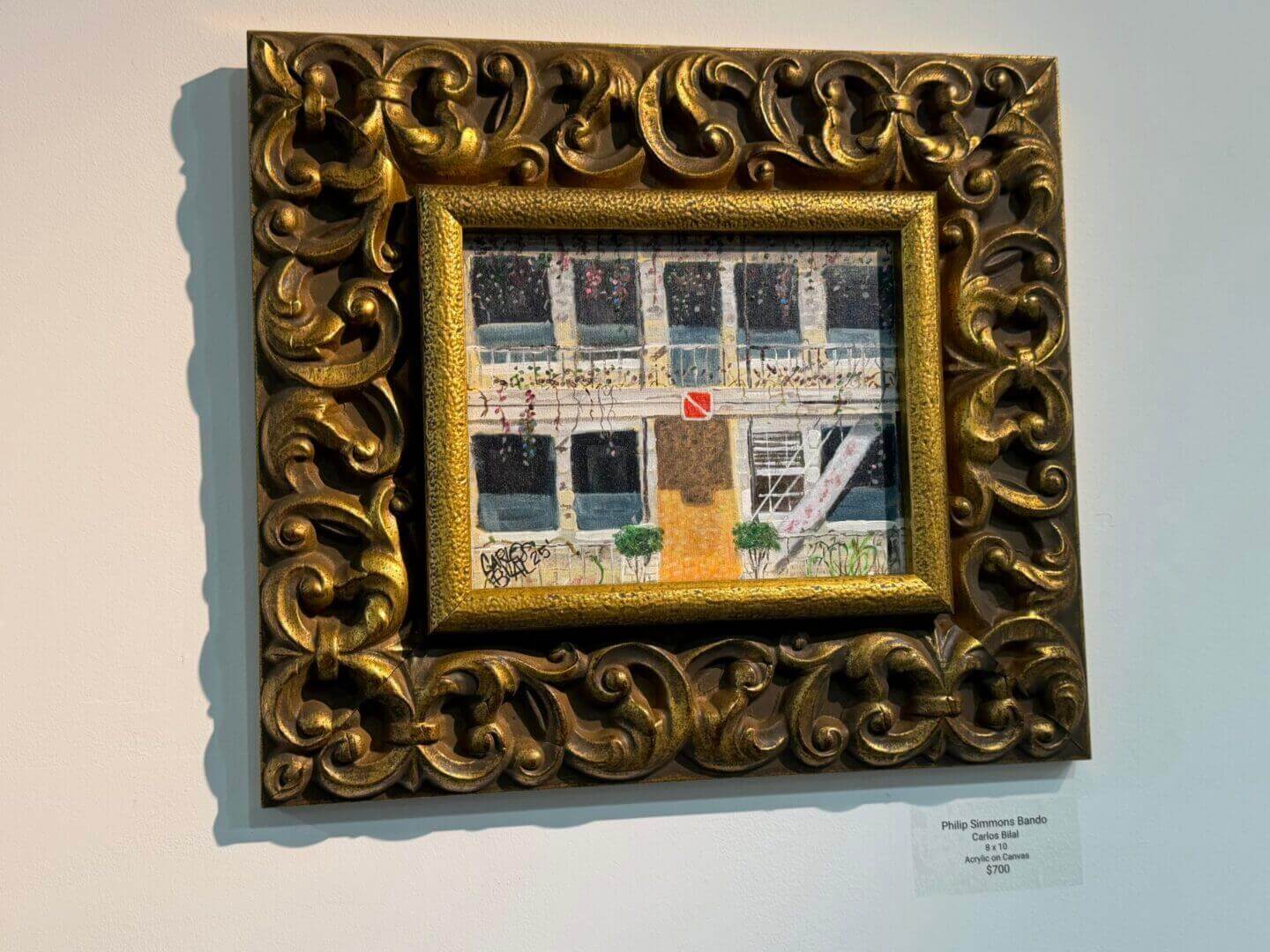 Framed painting on wall with ornate border.