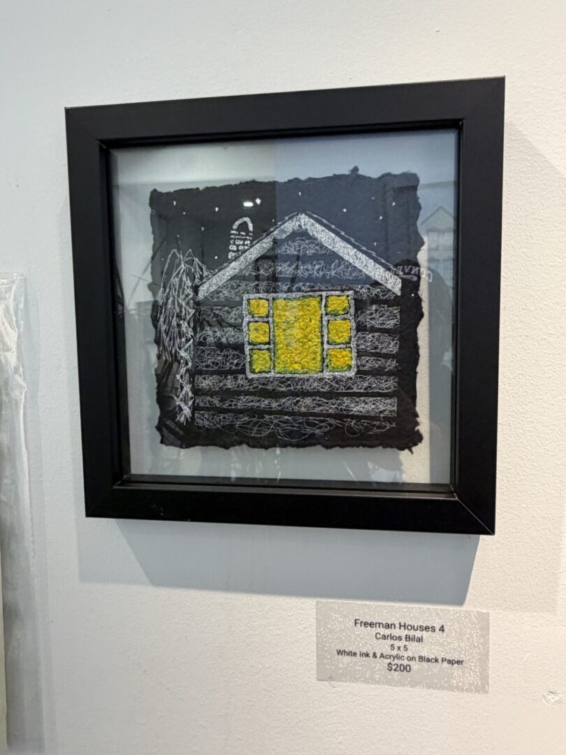 Framed artwork of a cabin at night.