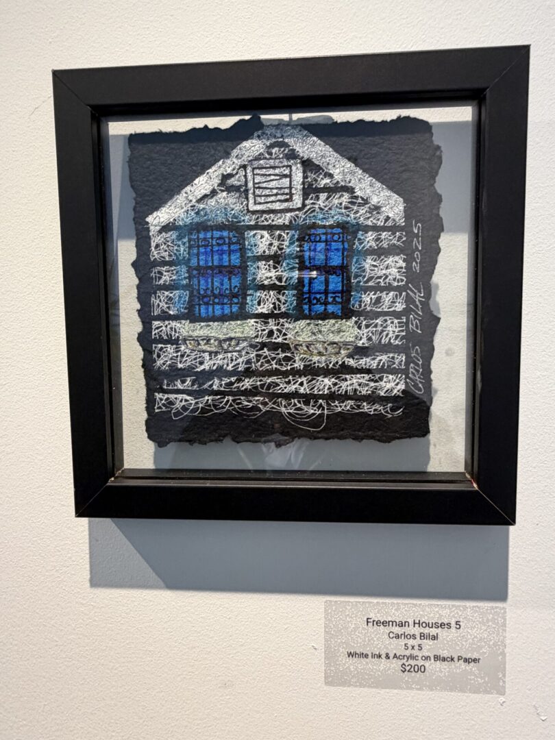 Framed abstract house artwork with blue windows.