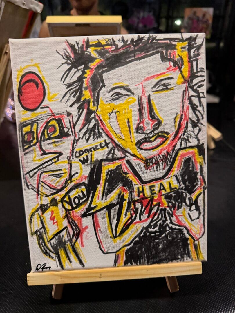 Abstract painting with faces and the word "HEAL".
