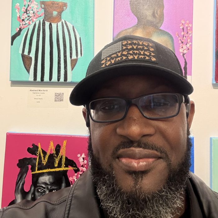 Man smiling in front of colorful artwork.